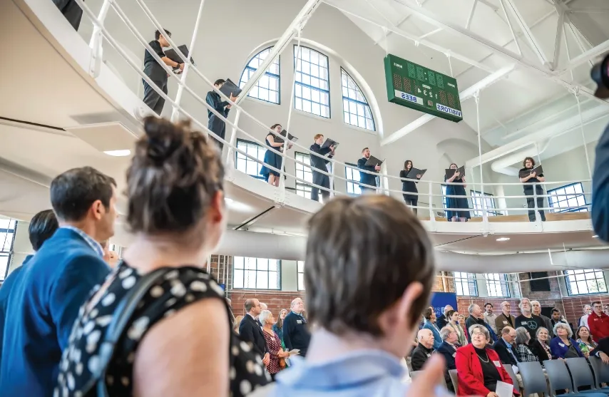 Students singing in the balcony of the new Higgins Hall.